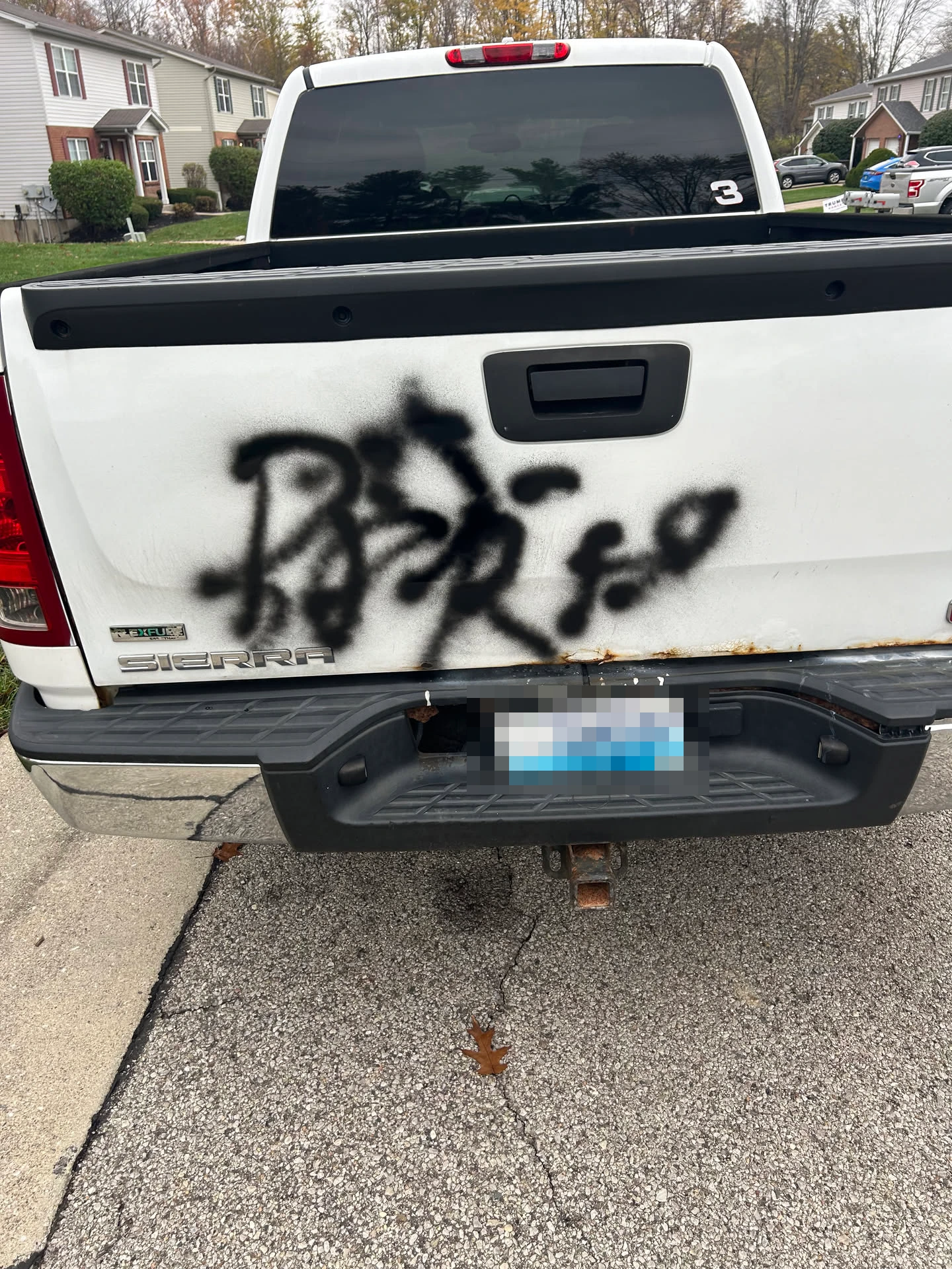 Image of a white truck with black spray paint on the back. The text is unclear.